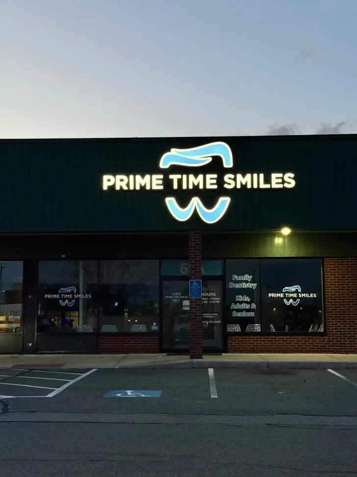 The Prime Time Smiles storefront at dusk, with the lit sign over the entrance.