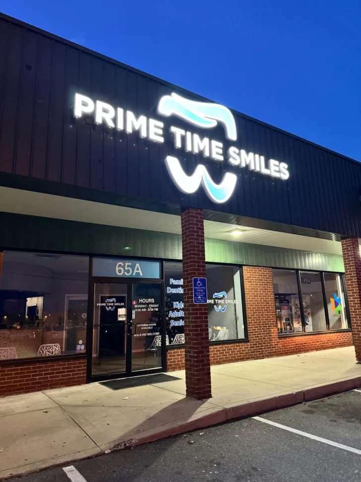 The Prime Time Smiles entrance at night, sign glowing over the door.